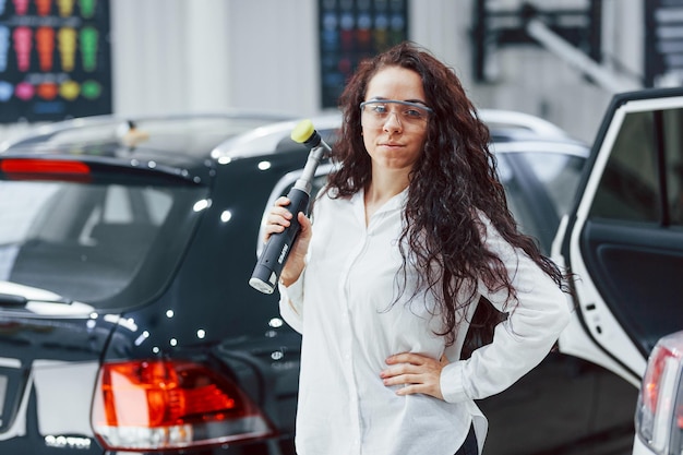 Kobieta ze sprzętem do czyszczenia nowoczesnego samochodu Koncepcja usługi