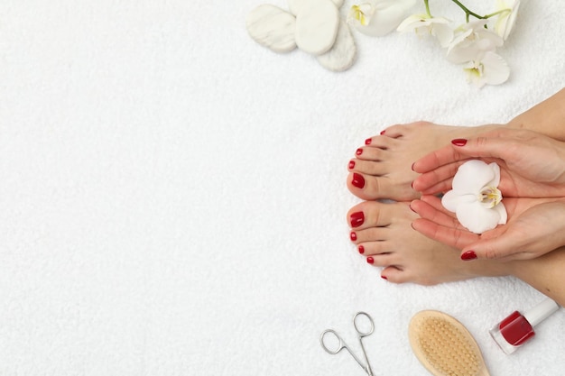 Kobieta ze stylowymi czerwonymi paznokciami po pedicure i kwiatami orchidei na białym ręczniku terry widok z góry Przestrzeń na tekst