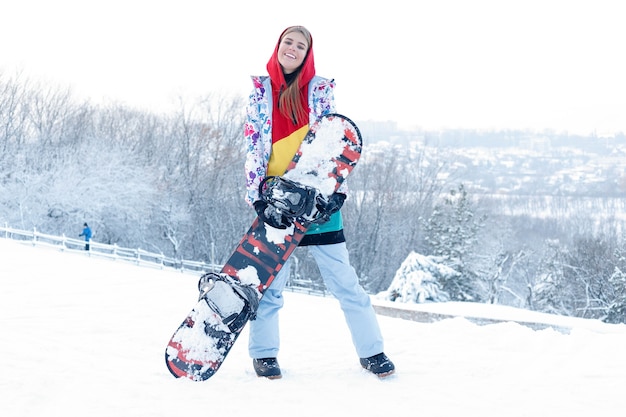 Kobieta Zima Odkryty Snowboardzie Koncepcja. Młoda Kobieta Trzyma Snowboard Na Ramionach, Odwraca Wzrok I Uśmiecha Się, Kopiuje Przestrzeń, Zbliżenie