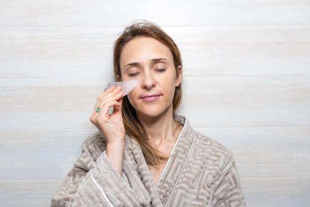 Zdjęcie kobieta zmniejszająca worki pod oczami z kamiennym masażerem do higieny osobistej