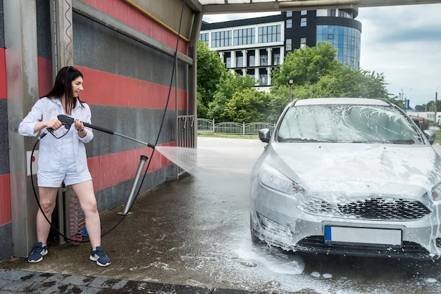 Kobieta Zmywa Piankę Wodą Na Samochodzie, Sprząta I Myje Samochód. Serwis