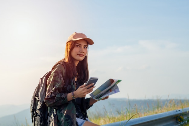 Kobiety azjatykcie z jaskrawym plecakiem patrzeje mapę. Widok z tyłu turysty na góry, Kobieta ręce za pomocą smartfona, trzymając gadżet