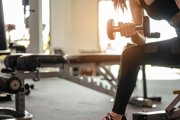 Kobiety ćwiczą z hantlami na sali gimnastycznej, aby zadbać o zdrowie o zachodzie słońca. fitness, trening, ćwiczenia na siłowni, styl życia i zdrowa koncepcja.