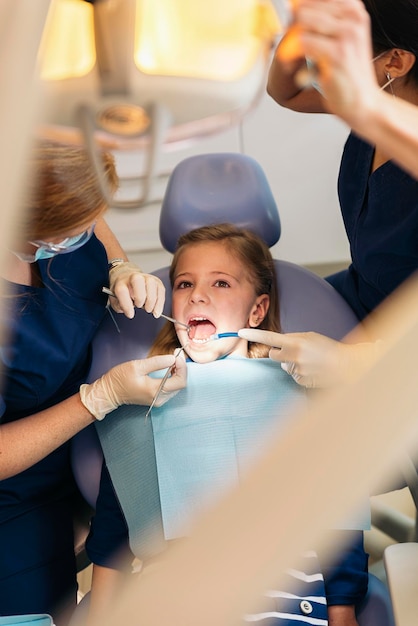 Kobiety dentystki badające dziewczynę w klinice