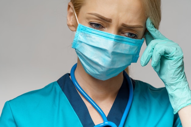 Kobiety doktorska jest ubranym maska ochronna i lateksowe rękawiczki ból głowy i stres