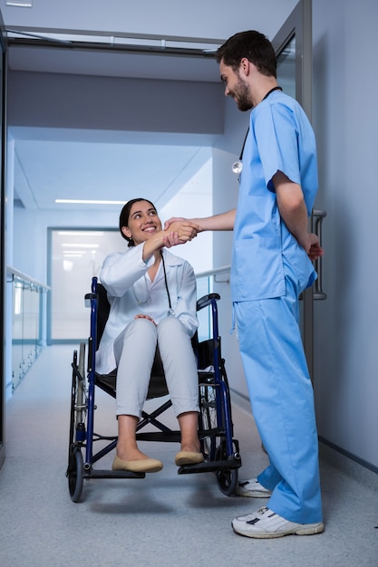 Kobiety Doktorski Obsiadanie Na Wózku Inwalidzkim I Drżenie Ręce Z Męską Pielęgniarką