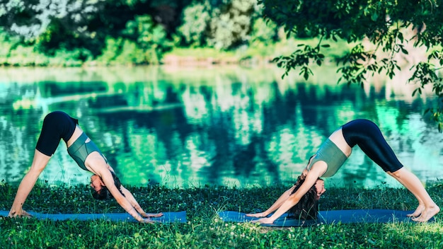 Kobiety jogi nad jeziorem Pozycja psa z głową w dół