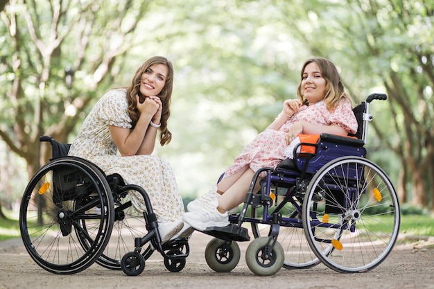 Kobiety korzystające z wózków inwalidzkich uśmiechające się do kamery na zewnątrz