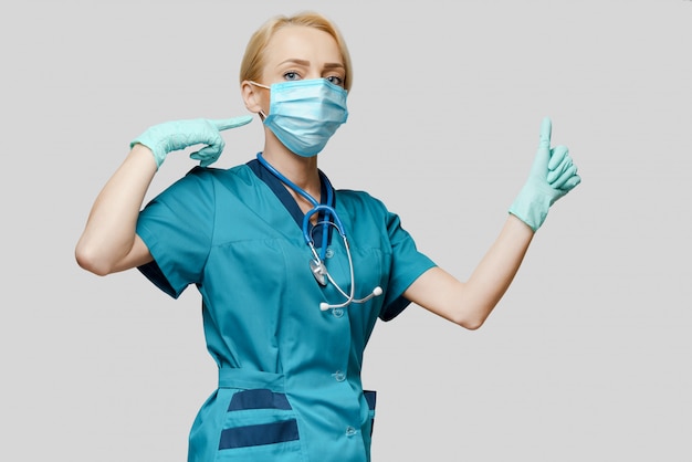 Kobiety lekarka jest ubranym maskę ochronną i lateksowe rękawiczki z stetoskopem