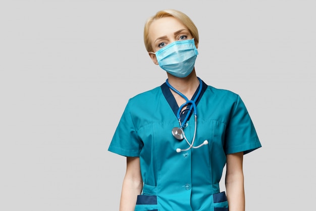 Kobiety lekarka jest ubranym maskę ochronną i lateksowe rękawiczki z stetoskopem