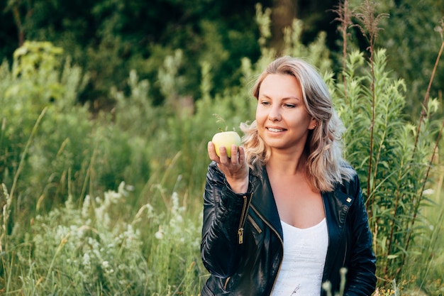 Kobiety mienie i patrzeć zielonego Apple podczas gdy relaksujący w parku.