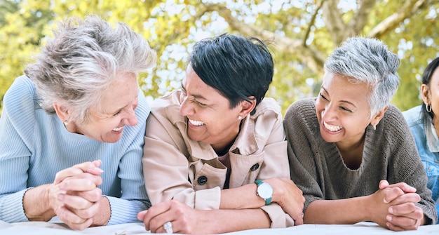 Kobiety na emeryturze i przyjaciele śmieją się razem w parku, aby połączyć dobre samopoczucie i relaksujący styl życia Szczęście zabawne i uśmiech starszych ludzi w przyjaźni międzyrasowej na kocu w naturze
