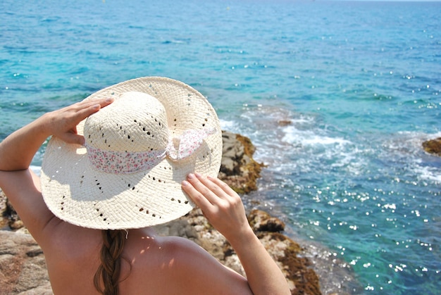 Kobiety obsiadanie na morzu kołysa patrzeć horyzont z jego kapeluszem