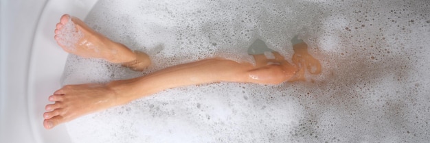 Kobiety piękne smukłe nogi w kąpieli z wodą i pianką