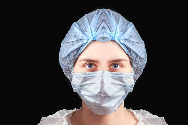 Kobiety pielęgniarka jest ubranym medyczną maskę i kapelusz na czarnym tle. Ochrona przed zakażeniem koronawirusem, pojęcie opieki zdrowotnej
