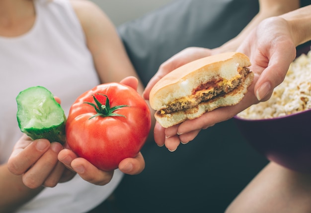 Kobiety posiadające burger, pomidor i ogórek