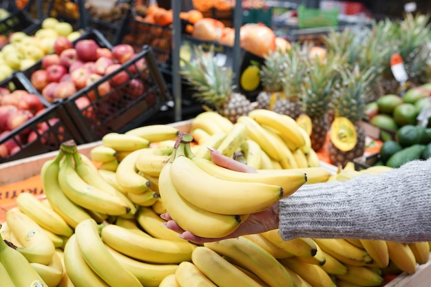 Zdjęcie kobiety ręcznie wybierają banany z licznika żywności w supermarkecie