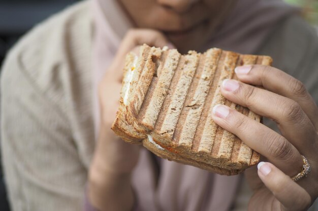 Kobiety ręcznie wybierają kanapkę z pomidorami z szynką i serem