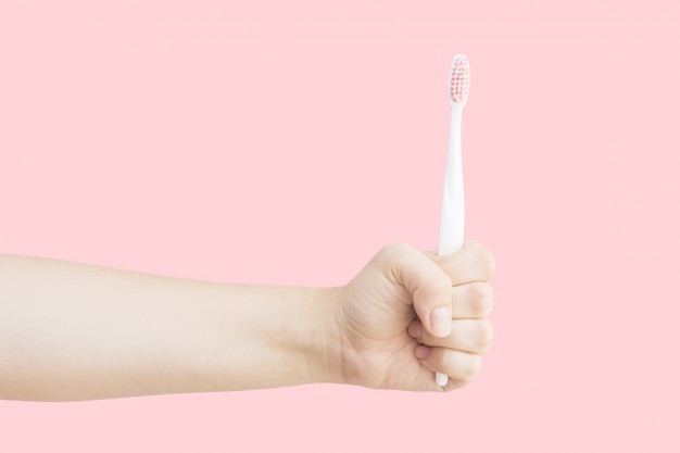 Kobiety ręka trzyma białego toothbrush na różowym tle