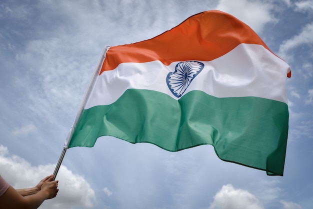 Kobiety ręka trzyma India flaga na niebieskim niebie