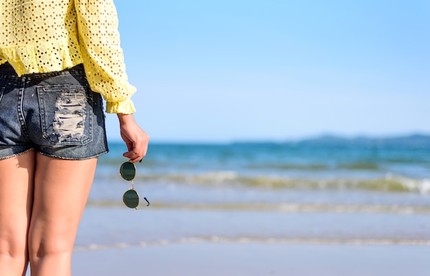 Kobiety ręki mienia okulary przeciwsłoneczni przy błękitnym morzem na plaży