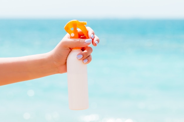 Kobiety ręki mienia sunblock kiść przy plażą