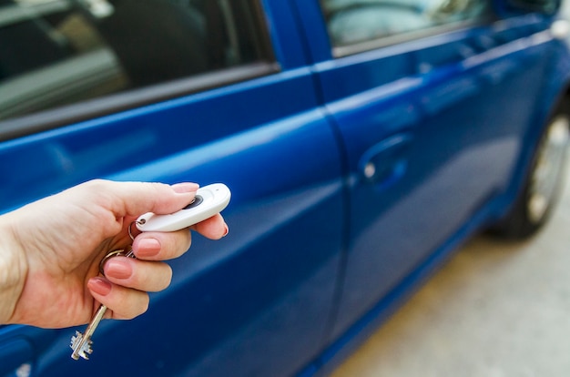 Kobiety ręki otwarty błękitny samochód z dalekim samochodu kluczem