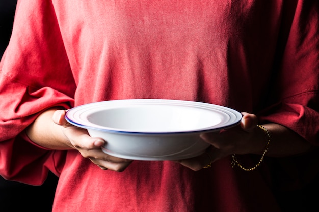 Zdjęcie kobiety trzymają białe talerze w dłoniach.