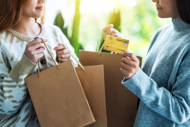 Kobiety trzymające torby na zakupy i kartę kredytową na zakupy