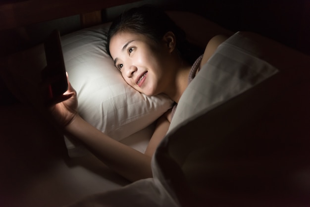 Kobiety use telefon komórkowy i kłamać na łóżku