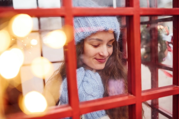 Kobiety w ciepłych ubraniach bawią się na stacji telefonicznej. Zobacz przez szybę.