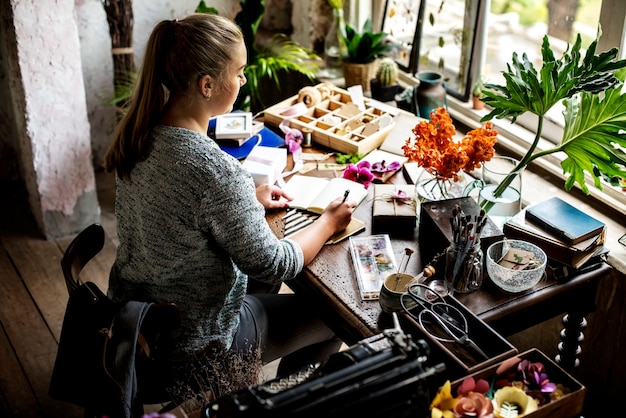 Kobiety writing na notatniku na workspace dekorował z kwiatem