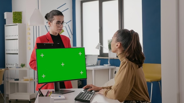 Kobiety wykonujące pracę zespołową z zielonym ekranem na komputerze, koledzy korzystający z izolowanego szablonu makiety z miejscem kopiowania klucza chroma na ekranie monitora. Pusta kopia tło w biurze.