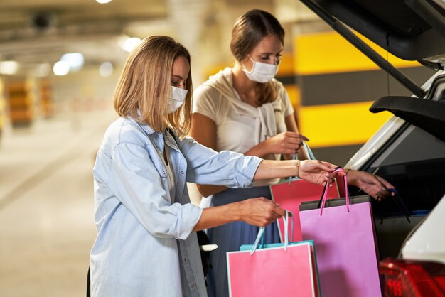 kobiety z torbami na zakupy w maskach na podziemnym parkingu