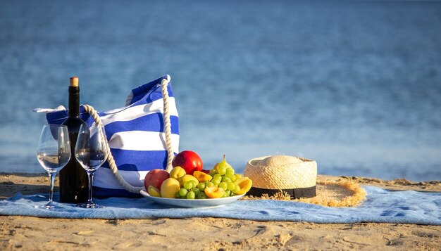 Koc piknikowy, wino, owoce, piękna morska plaża. Selektywne skupienie