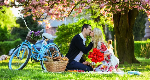 Kochać wszystko w niej ciesząc się przyrodą razem podczas pikniku w parku miejskim mężczyzna i kobieta odpoczywają z koszem na jedzenie Romantyczna para pod sakura zakochana para na zielonej trawie