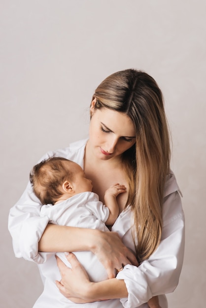 Kochająca matka nosi w domu swoje nowo narodzone dziecko. portret szczęśliwej matki trzymającej śpiące dziecko w ramionach. Mama przytula swoją 4-miesięczną córeczkę