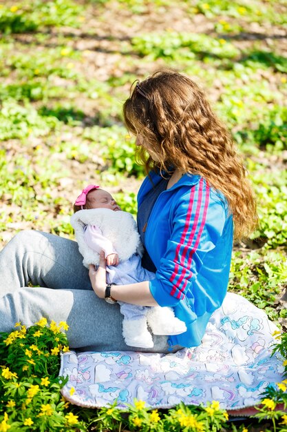 Kochająca matka z nowo narodzonym dzieckiem na ramionach. Piękna mama z uroczym śpiącym nowo narodzonym dzieckiem na naturze na zewnątrz. Pierwszy tydzień życia dziecka. Szczęśliwe macierzyństwo i zgodna rodzina.