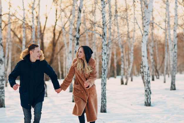 Kochająca młoda para spacerująca, bawiąca się i bawiąca się w zimowym parku leśnym