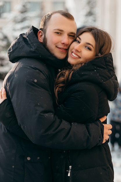 Kochająca się para w łagodnym uścisku na tle zaśnieżonego miasta. Wysokiej jakości zdjęcie