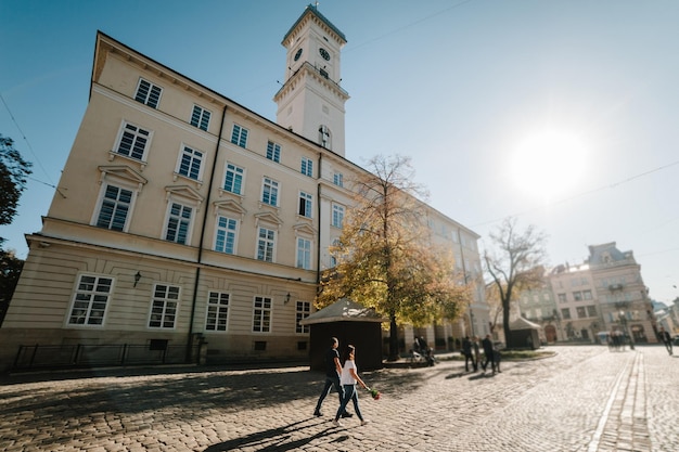 Zdjęcie kochająca szczęśliwa para chłopiec i dziewczynka z bukietem kwiatów w walentynki na świeżym powietrzu mężczyzna i kobieta spacerują ulicami miasta