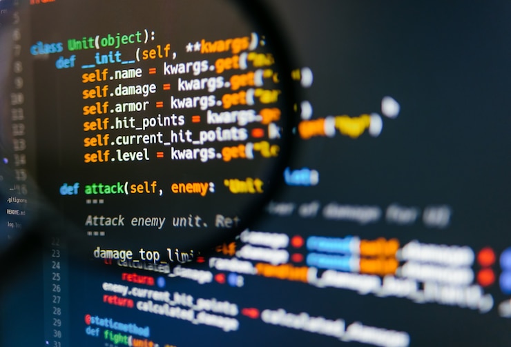 Zdjęcie kod programu na ekranie komputera w lupie. zbliżenie