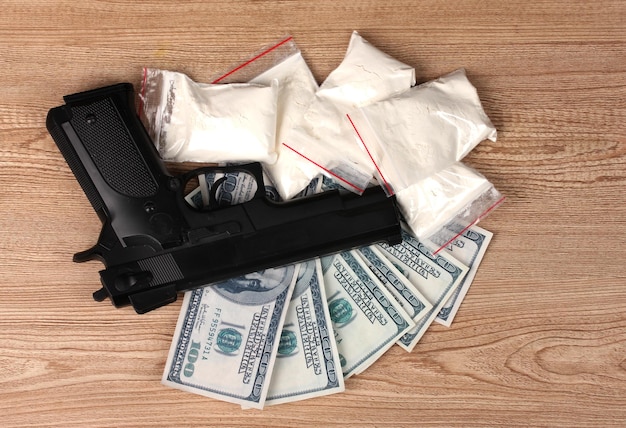 Kokaina w paczkach dolarach i pistoletu na drewnianym tle