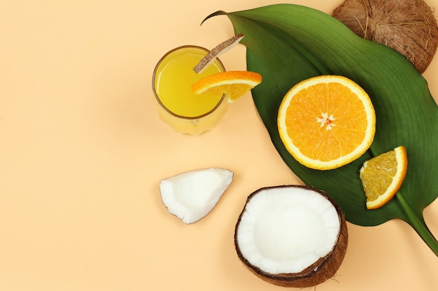 Kokos, orzech i sok pomarańczowy, liść palmowy na beżowym tle