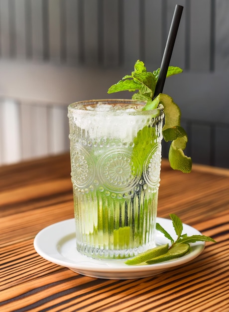 Koktajl alkoholowy Mojito na drewnianym stole pod ciemną ścianą z miejsca na kopię