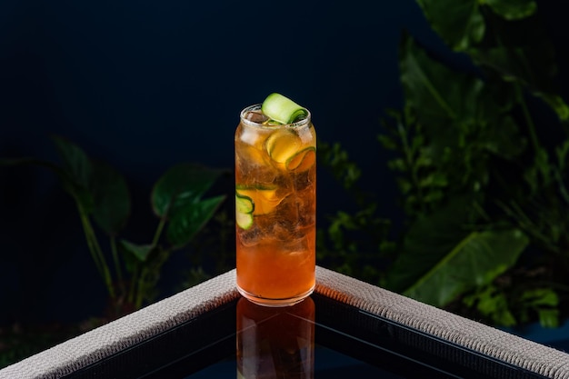 Koktajl alkoholowy na przezroczystym stole na niebieskim tle i roślinach