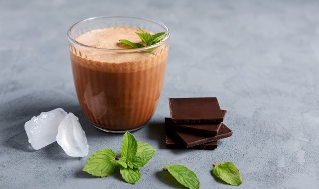 Zdjęcie koktajl czekoladowy, smoothie z lodem, kawałkami czekolady i miętą w szklanej szklance