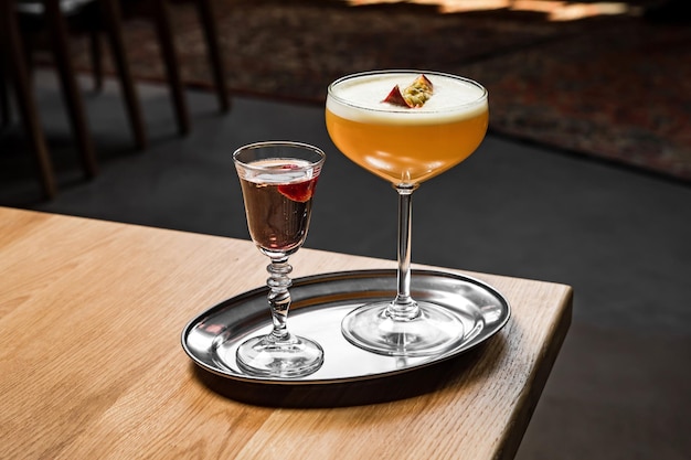 Koktajl martini gwiazdy porno z marakui i wódką podawany na srebrnej tacy przy drewnianym stole w barze lub restauracji zdjęcie poziome