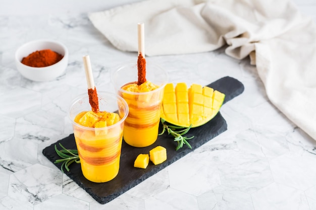 Koktajl meksykański z mangonadą z mango z sosem chamoy i słomką tamaryndowca w plastikowych szklankach