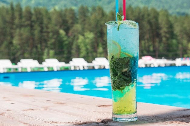 Koktajl Mojito z limonką i miętą w szklance typu highball na basenie